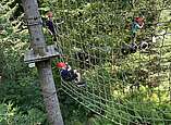 Jugendliche bewältigen gemeinsam einen Parcours im Kletterpark