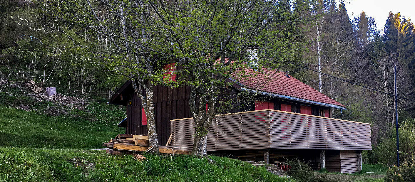 Holzhütte in der Natur mit Terasse und Baum davor