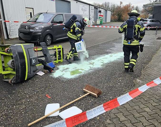 Feuerwehrangehörige bringen Chemikalienbinder auf das Medium auf
