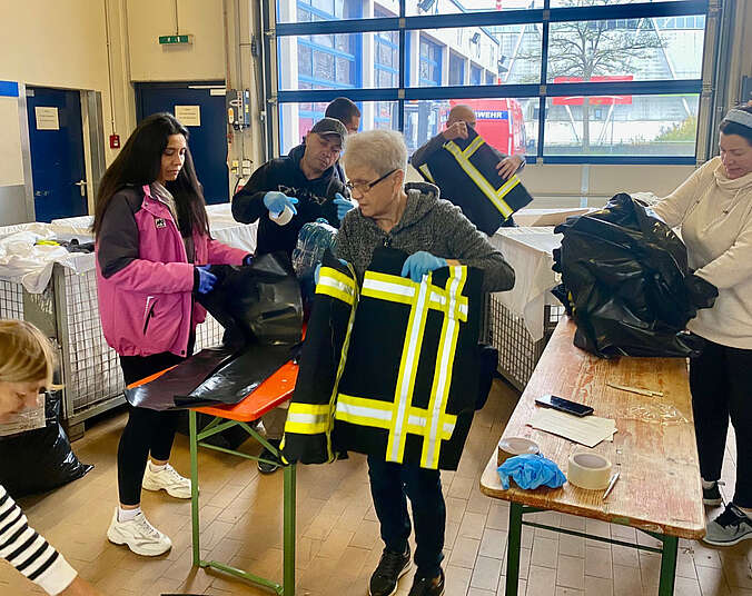 Menschen packen Schutzkleidung ein. (Foto: Stadt Friedrichshafen)