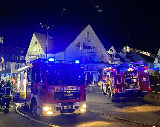 Feuerwehrfahrzeuge und Einsatzkräfte löschen mit Schläuchen Brand.
