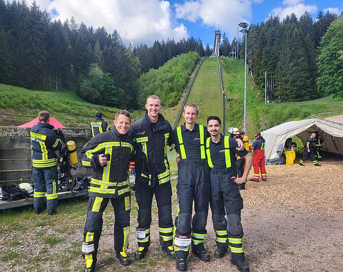 4 Feuerwehrleute vor der Skisprungschanze Schonach