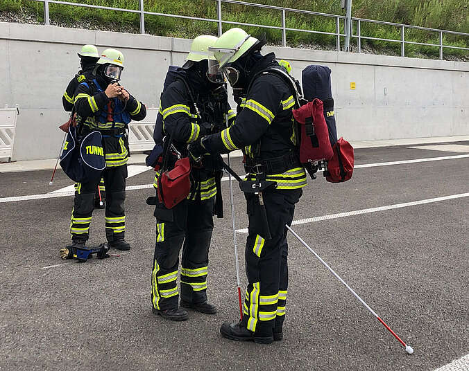Feuerwehrkräfte mit Atemschutz und Blindenstöcken